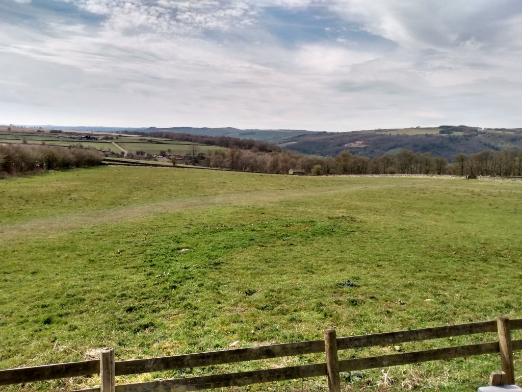 View over countryside with a fence in the foreground. Shows a boundary with something beautiful on the other side.
